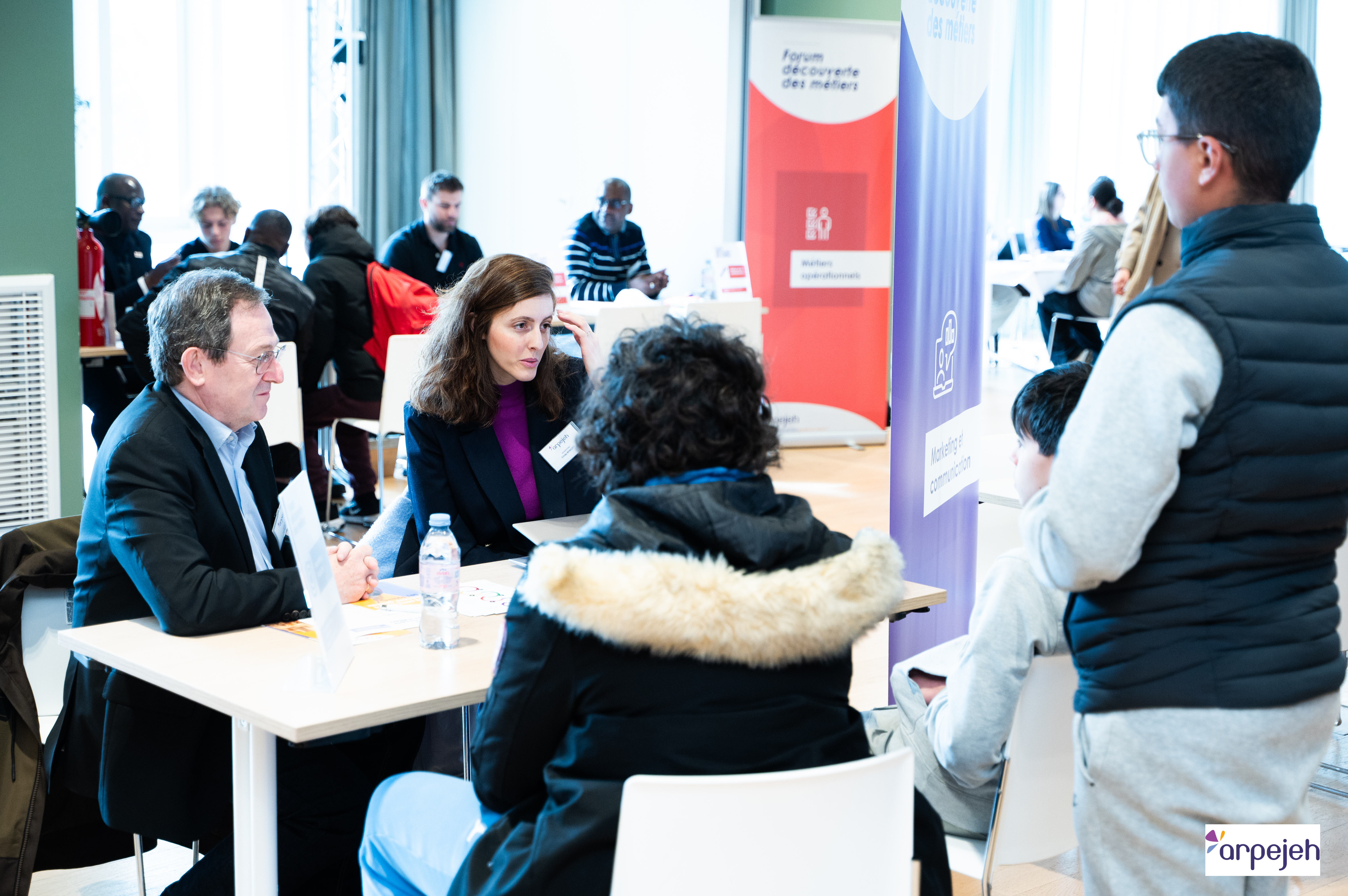 Des collaborateurs échangent avec des jeunes à leur stand lors du Forum Découverte des métiers organisé par arpejeh à Saint-Ouen.