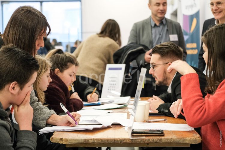 Les jeunes sont assis face à des exposants et échangent ensemble.