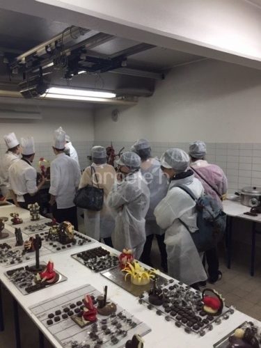 Les professionnels visitent l'atelier chocolaterie. Sur les tables se trouvent des créations en chocolat.