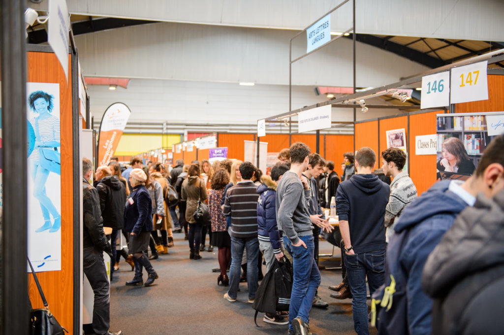 Une foule de jeune sont devant des stands lors d'un salon étudiant